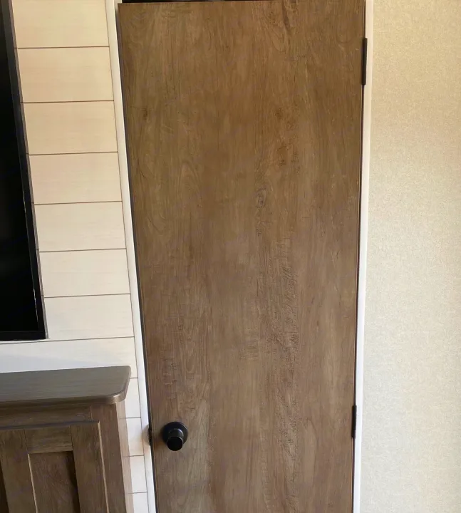 Inside an RV rental, showing a wood grain door, textured wall, and shiplap paneling with a TV and cabinet.. Forest River Salem Cruise Lite 2021