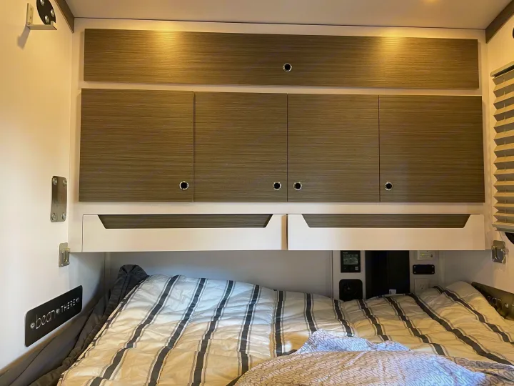 Cozy RV rental interior with a comfortable bed, wood-grain overhead storage cabinets, and ambient lighting, perfect for travel.. Bean Mean Bean 2022