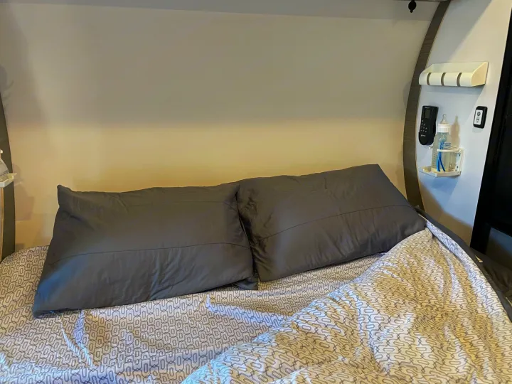 Comfortable RV rental bedroom with patterned bedding, dark pillows, and convenient wall amenities including a baby bottle.. Bean Mean Bean 2022