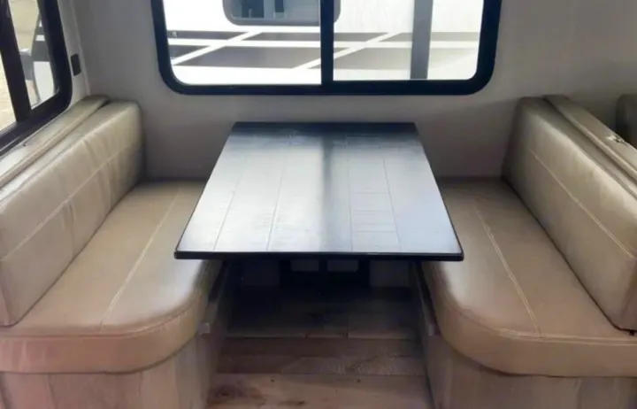 This RV rental features a clean dinette with comfy light-colored bench seats and a dark table, ideal for meals.. Keystone RV Outback Ultra-Lite 2020