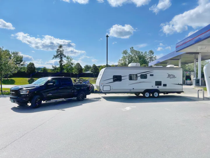 Black truck with bikes towing a white RV at a gas station. Perfect for an RV rental road trip!. Jayco Jay Flight SLX 2017