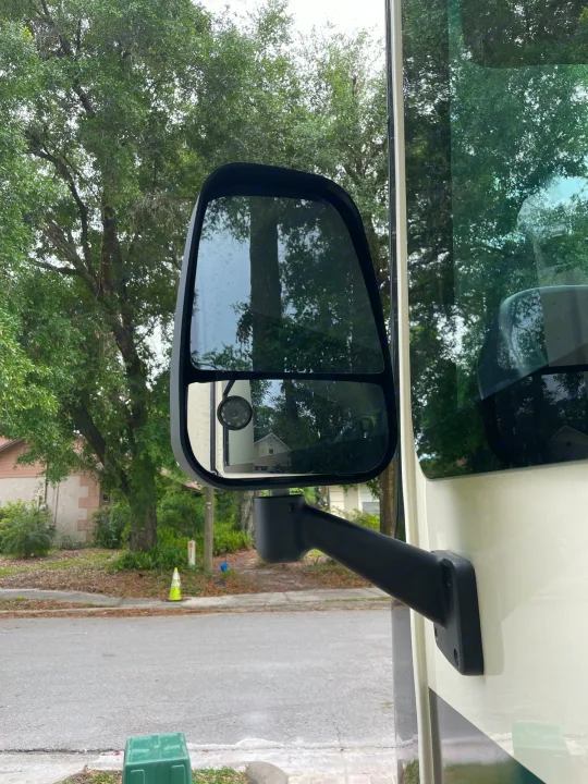 Close-up of an RV rental's side mirror, reflecting a residential street, trees, and distant houses.. Other Other 2022