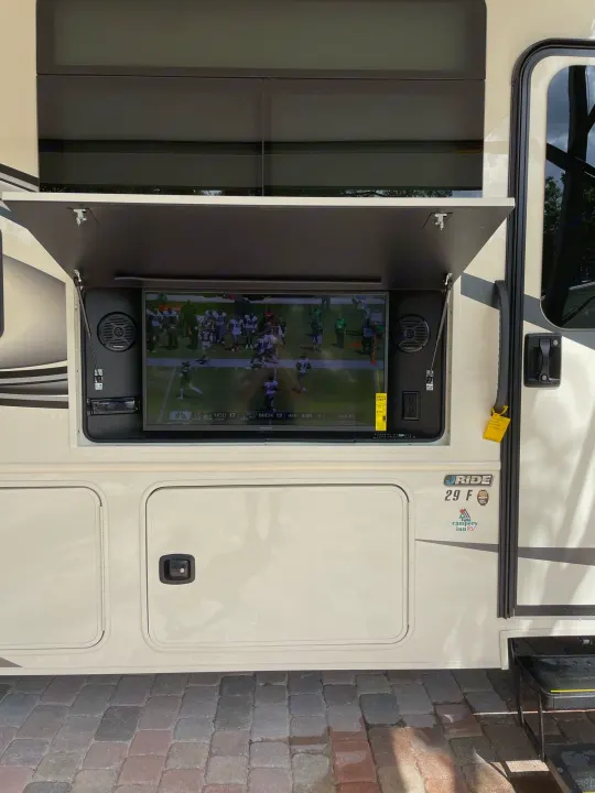 RV rental with an outdoor TV displaying a football game, perfect for tailgate parties on a paved surface.. Other Other 2022