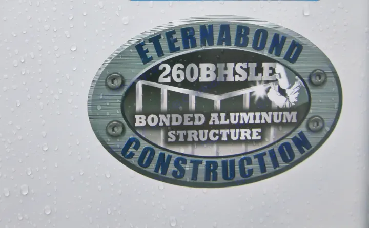 Close-up of an RV rental's ETERNABOND "Bonded Aluminum Structure Construction" decal. Water droplets visible.. Prime Time RV 260BHSLE 2022