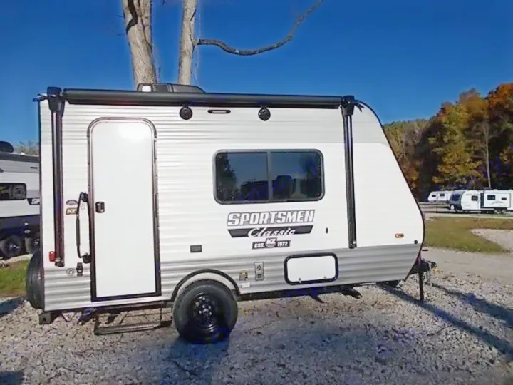 A sleek, new Sportsmen Classic travel trailer for RV rental, ideal for camping and outdoor adventures under a blue sky.. Sportsmen Classic 2022