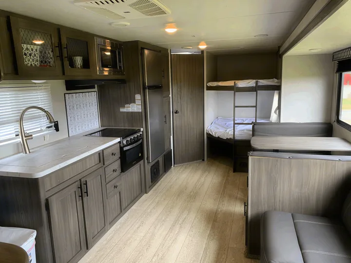 Spacious rv rental interior showcasing a full kitchen, modern dinette, and cozy bunk beds. Perfect for family adventures.. Other Other 2021
