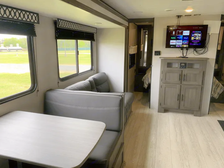 Spacious RV rental interior showcasing a modern living space with a dinette, sofa, and entertainment center, ideal for comfortable travel.. Other Other 2021