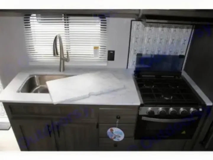 RV rental kitchenette: A compact kitchen with a sink, cutting board, stove, and oven, perfect for travel.. Other Other 2021