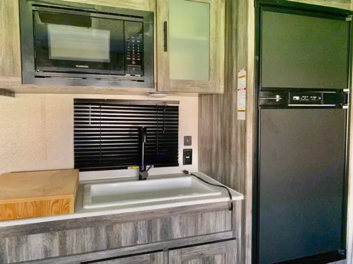 RV rental interior: compact kitchen area featuring a Furrion microwave, sink, and two-door refrigerator.. Forest River Salem FSX PLATINUM 2020