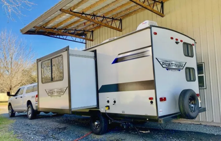 This Platinum travel trailer RV rental, with a slide-out, is parked and connected to a pickup truck under a shelter.. Forest River Salem FSX PLATINUM 2020
