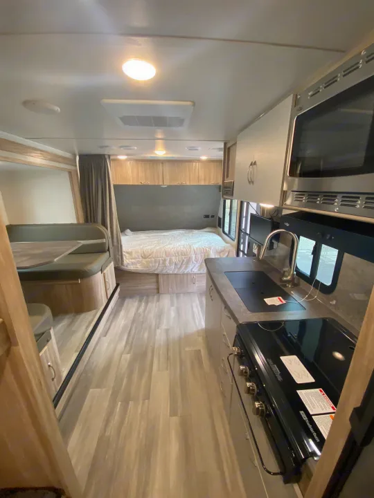 Step inside this RV rental, featuring a modern kitchen with stove/microwave, a comfy bed, and a versatile dinette area.. Winnebago Micro Minnie 2021