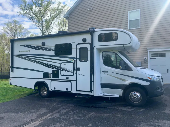 A white Sunseeker Class C RV rental, with black graphics, parked on an asphalt driveway.. Forest River Sunseeker 2022