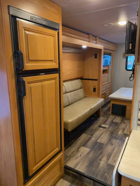 Modern RV rental interior with Dometic fridge, sofa, bunk, and wood accents. Explore comfortable travel in this motorhome.. Nexus Phantom 32P 2019
