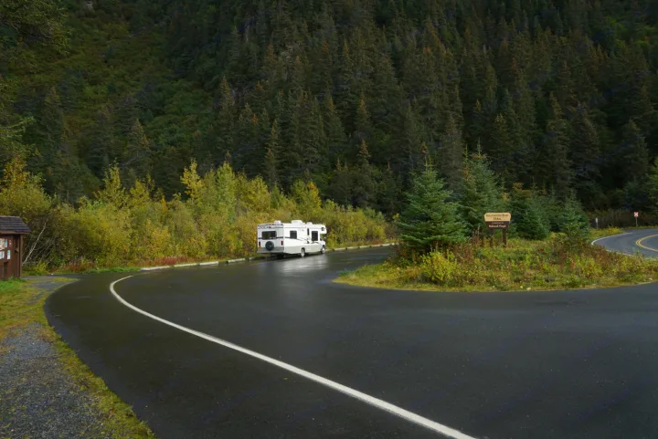 RV rental at wet road fork in Chugach National Forest, leading to Resurrection River Trail. Surrounded by lush Alaskan trees.. Fleetwood Tioga 2004