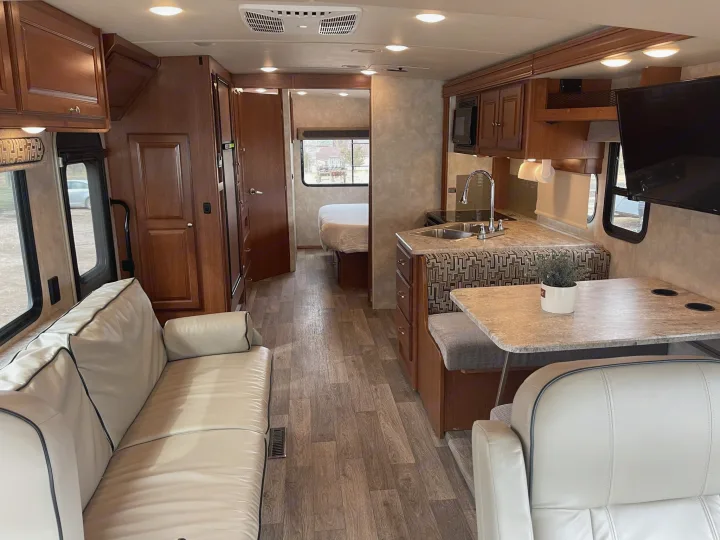 Spacious, modern rv rental interior, featuring living, kitchen, dining areas, and a visible bedroom.. Winnebago Vista 2018