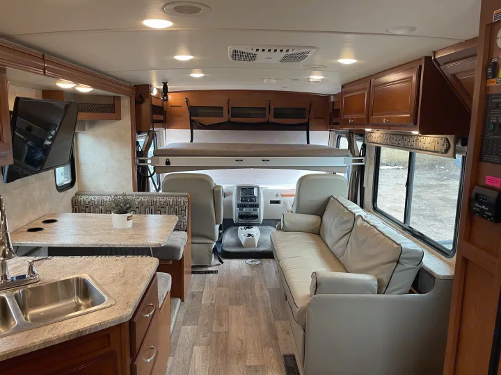Spacious and modern RV rental interior featuring a kitchen, dinette, living area, and overhead bunk for comfortable travel.. Winnebago Vista 2018