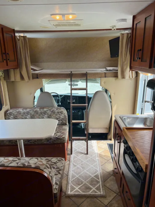 Step inside this cozy RV rental, showcasing a comfortable dinette, an overhead bunk with ladder, and a functional kitchen.. Forest River Sunseeker LE 2013
