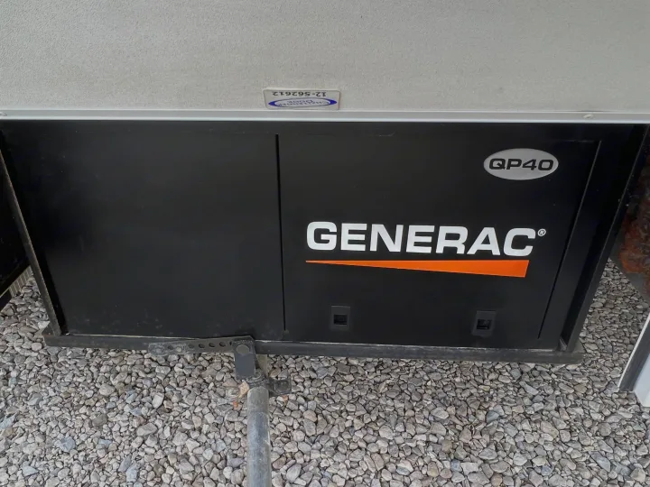 A black Generac QP40 generator unit, vital for an RV rental, is pictured on gravel.. Forest River Sunseeker LE 2013