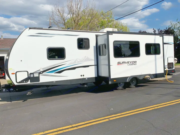 Modern white 'Surveyor Legend' travel trailer with extended slide-out.. Forest River Surveyor Legend 296QBLE 2021