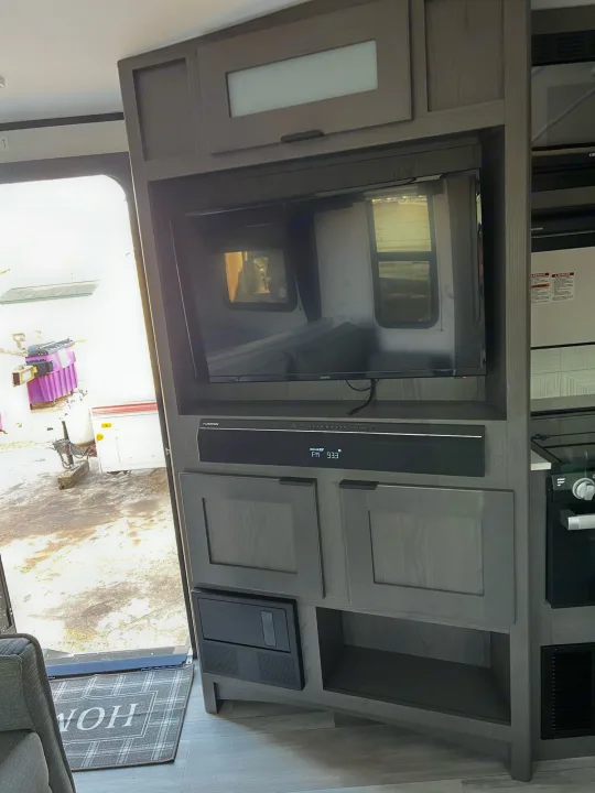 RV rental interior featuring a TV, Furrion soundbar (FM 93.3), and stylish cabinetry. Open door shows outside.. Other Other 2021
