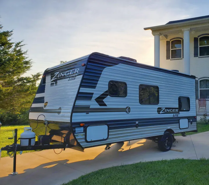 A Zinger Lite travel trailer on a driveway at sunset, a perfect RV rental option for your next trip.. Crossroads RV Zinger 2021