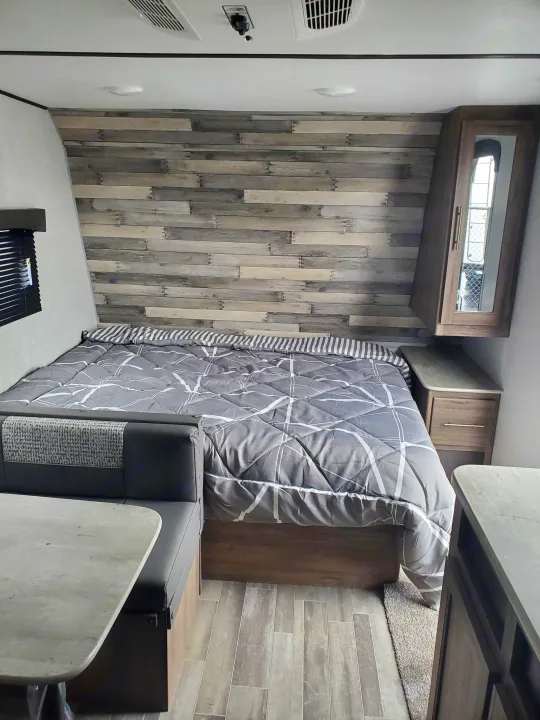 Compact rv rental interior featuring a bed, dinette, and modern wood-look decor.. Crossroads RV Zinger 2021