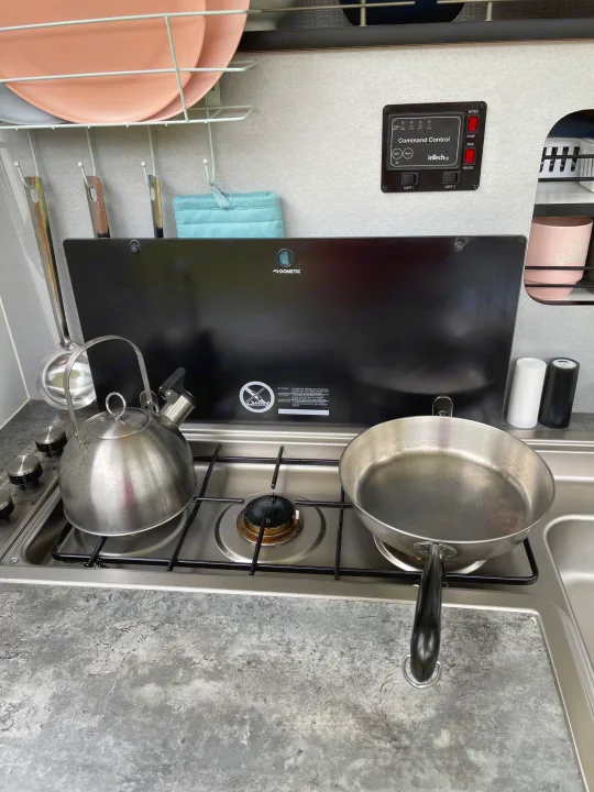 Compact RV rental kitchen showing a Dometic stove, kettle, pan, and inTech Command Control panel for systems.. InTech RV InTech RV Trailer 2018