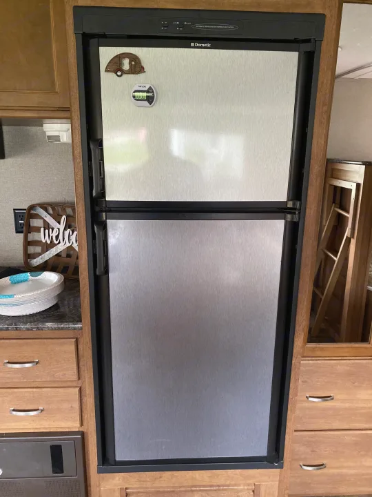 RV rental interior featuring a Dometic stainless steel refrigerator, wooden cabinets, and counter space.. Keystone RV Springdale 2017