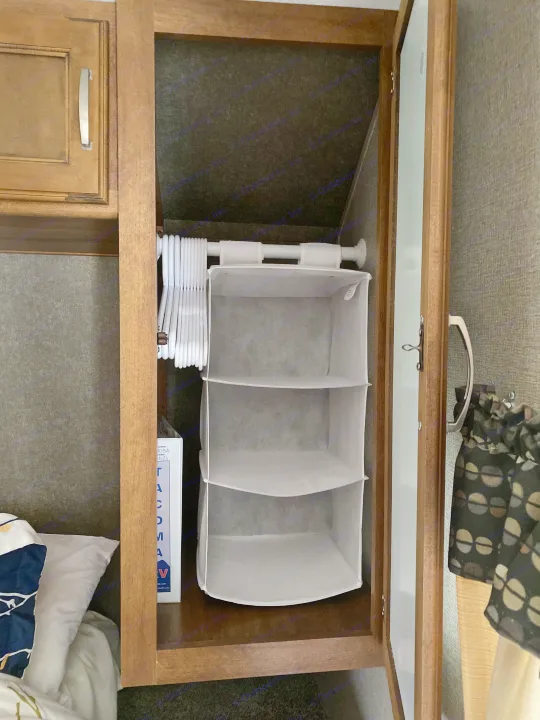 Open closet in an RV rental, featuring a tension rod with hangers, a hanging fabric organizer, and storage space.. Keystone RV Springdale 2017