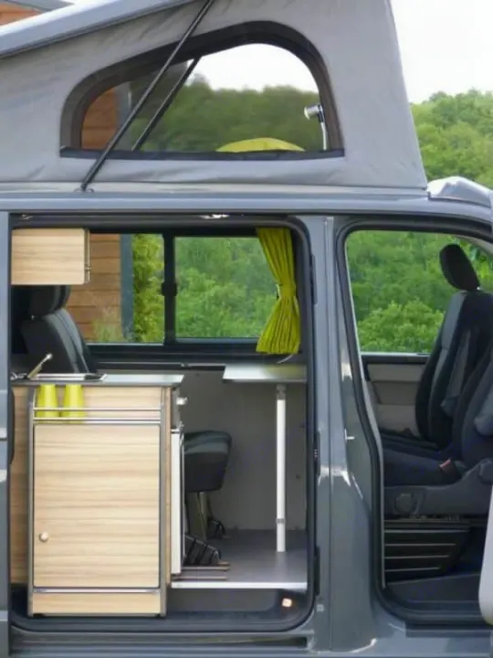 RV rental: Inside a pop-top camper van showing its compact kitchen unit with sink, dining table, and seating.. Volkswagen Transporter T6.1 2022