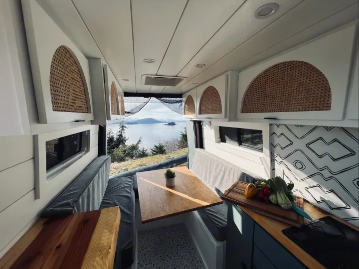Spacious RV rental interior with a bright dining area, kitchen setup, and panoramic lake views for your travels.. Freightliner Sprinter 2011