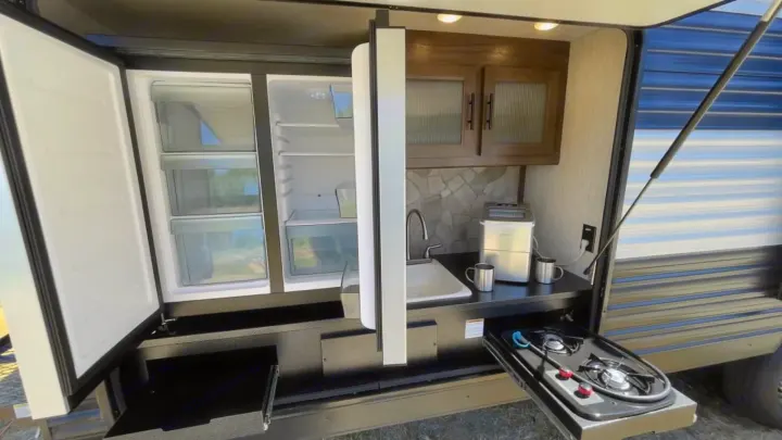 This rv rental features an exterior kitchen: fridge, sink, pull-out stove, ice maker, and cabinets.. Forest River Cherokee Grey Wolf 2020