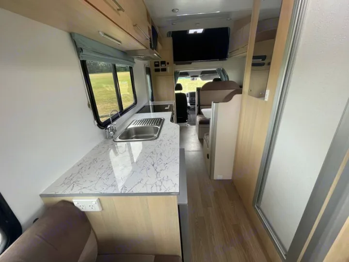 Spacious RV rental interior featuring a modern kitchen with a sink, a comfortable dining area, and a private bathroom.. Mercedes-Benz Sprinter 2018