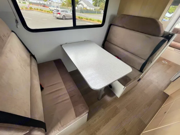 RV rental interior: A cozy dinette with tan benches, a table, and seatbelts for comfortable travel.. Mercedes-Benz Sprinter 2018
