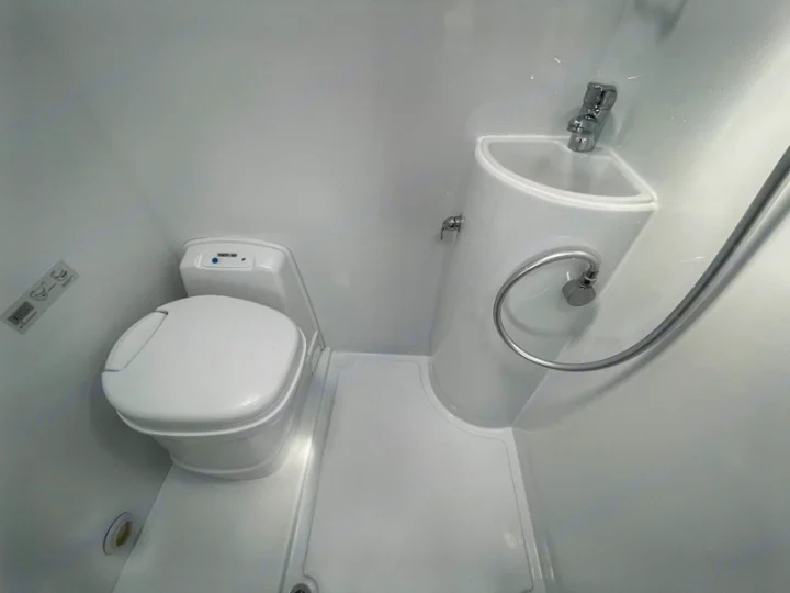 RV rental wet bath interior: compact white toilet, corner sink with faucet, and shower head for convenient use.. Mercedes-Benz Sprinter 2018