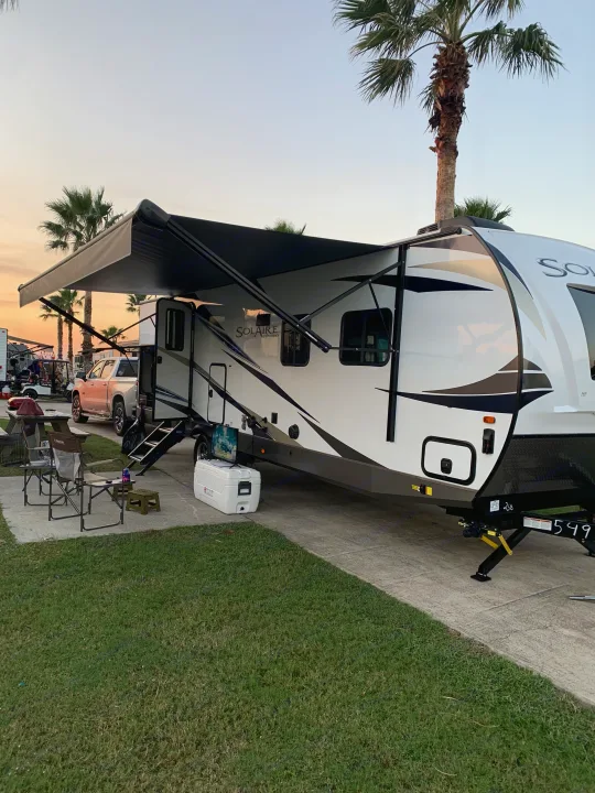 RV rental with extended awning & outdoor setup under palm trees. Perfect for your next camp adventure.. Forest River Palomino Solaire 2021
