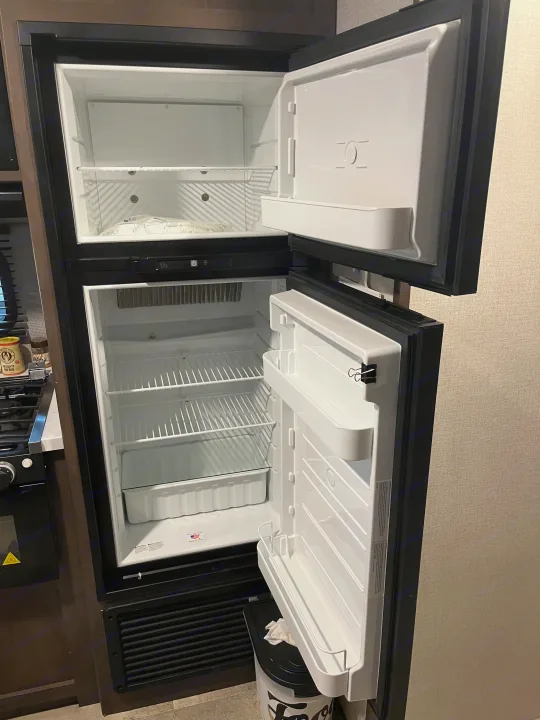 Clean, empty refrigerator and freezer in an RV rental kitchen, ready for your trip.. Coleman QBWE295 2021