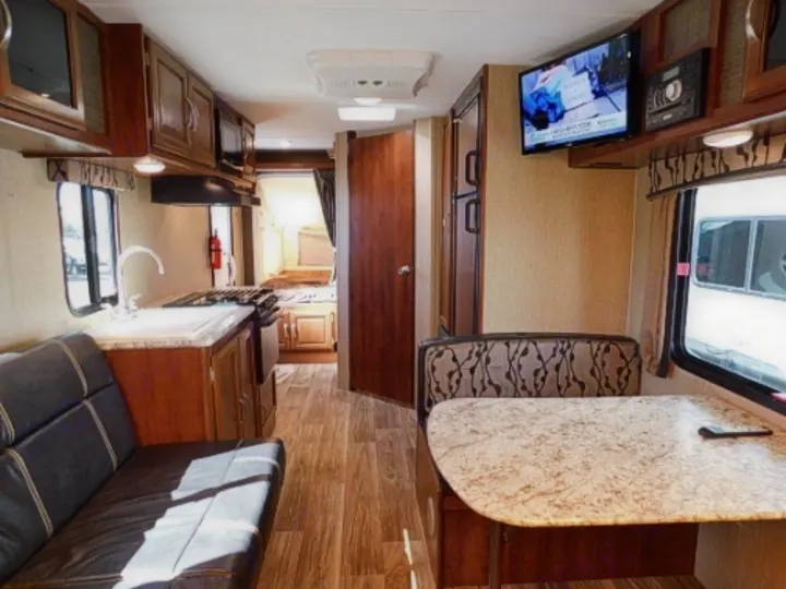 Clean and inviting RV rental interior featuring a kitchen, dinette, and sofa. Ideal for travel adventures.. Keystone RV Passport Express 2016