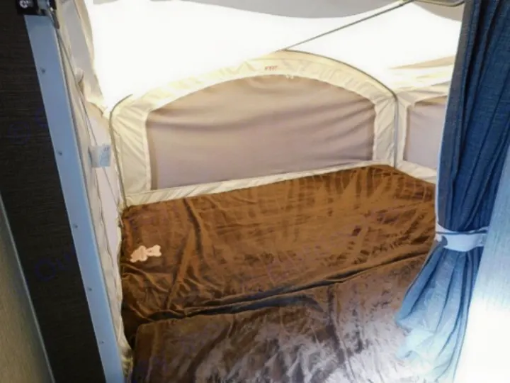 This RV rental pop-up camper features a cozy bed with a brown blanket & soft fabric walls.. Keystone RV Passport Express 2016