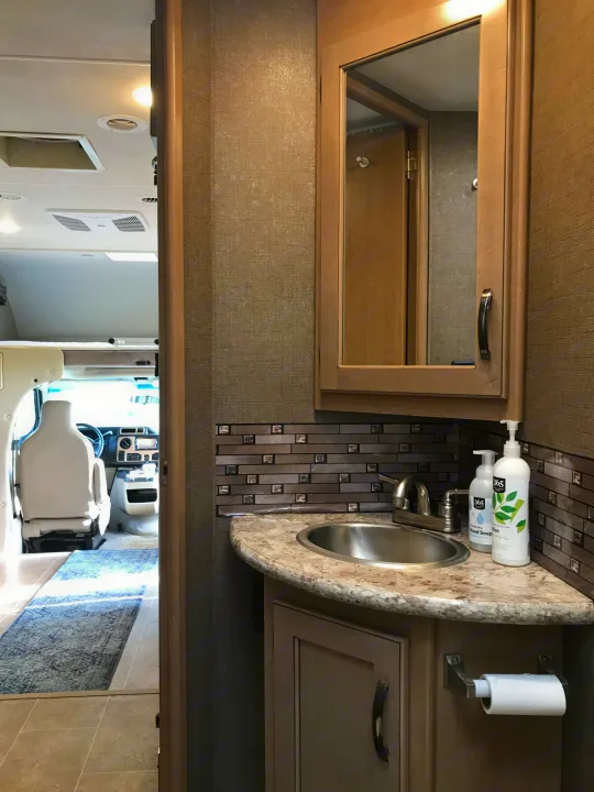 Step inside this RV rental's inviting interior, featuring a well-appointed bathroom vanity and a peek into the driver's cabin.. Thor Chateau 2019