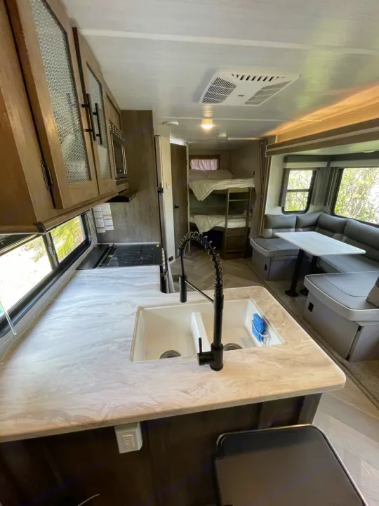 Modern RV rental interior: kitchen with dual sink, large dinette, and cozy bunk beds. Spacious living for road trips.. Forest River Other 2021