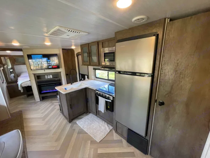 Spacious RV rental interior featuring a modern kitchen, living area with TV and fireplace, and cozy bedroom for travel.. Forest River Other 2021