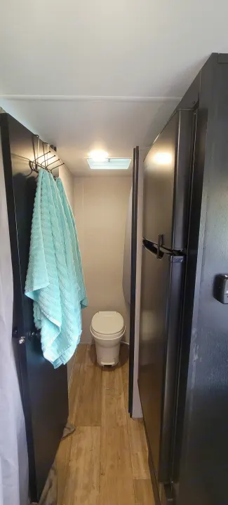 RV rental: Compact interior showing white toilet, light blue towels on left door, and black refrigerator right.. Forest River Cherokee Wolf Pup 2022