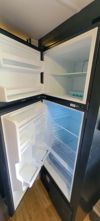 Clean, empty two-door refrigerator and freezer inside an RV rental, offering spacious storage for your travel food needs.. Forest River Cherokee Wolf Pup 2022