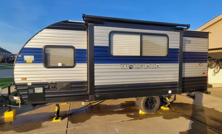 This "Wolf Pup" travel trailer, ideal for an rv rental adventure, is parked and leveled on a driveway under a clear sky.. Forest River Cherokee Wolf Pup 2022