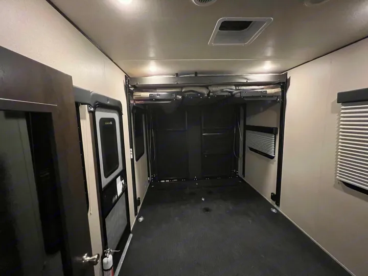 Spacious RV rental toy hauler garage featuring elevated bunk beds, a durable rubber floor, and tie-downs for versatile use.. Grand Design Momentum 2022