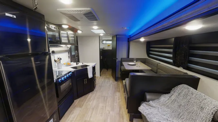 Inside a modern travel trailer RV rental, featuring a sleek kitchen, comfortable booth dining, and lounge area.. Forest River Cherokee Grey Wolf 2020