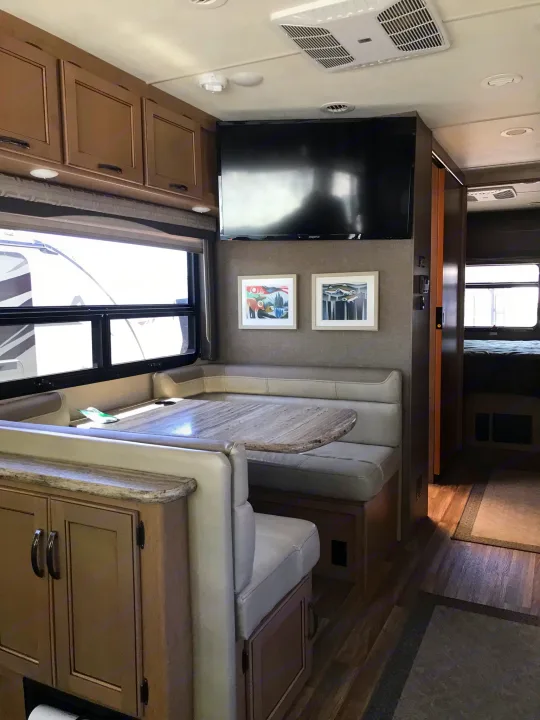 Comfortable RV rental interior featuring a dinette, large TV, and cozy living space, ideal for travel adventures.. Thor Motor Coach A.C.E 2018