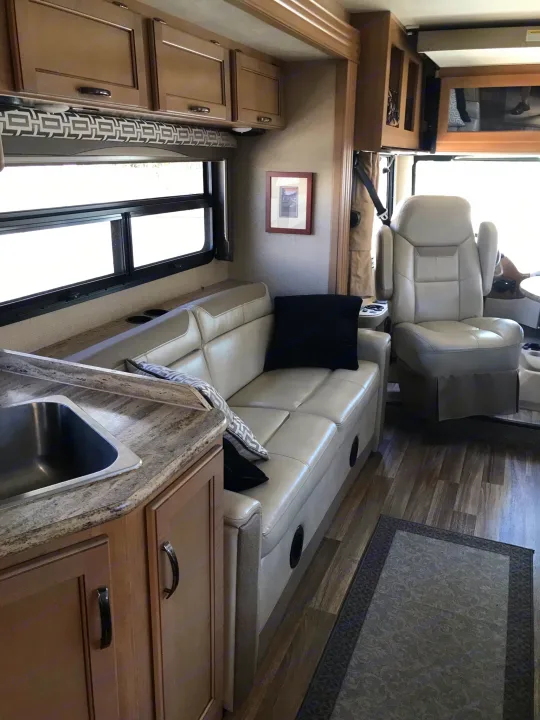 Spacious RV rental interior featuring a modern kitchen, comfortable seating, and cockpit area.. Thor Motor Coach A.C.E 2018