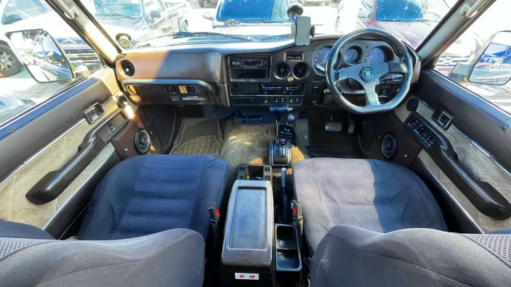 Inside a well-maintained classic vehicle, showcasing the dashboard, steering wheel, and seats. Ideal for a unique rv rental experience.. Toyota LandCruiser HJ61 VX 1989
